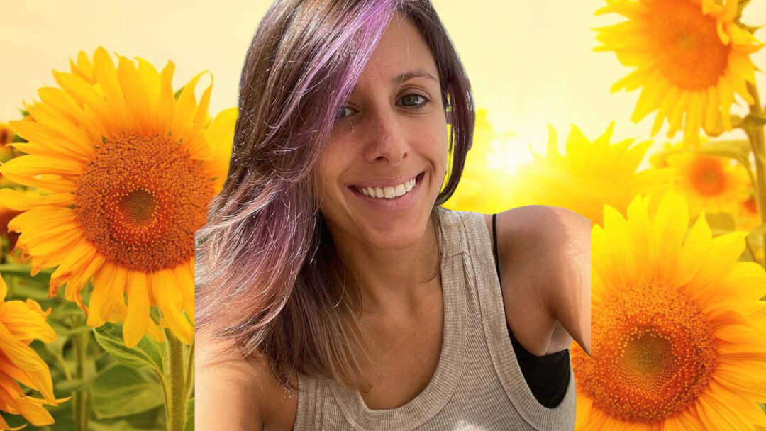 Jordana from Mothers Mary backdropped by sunflowers during an interview with Evi OMsGurl about teaching mothers how to heal