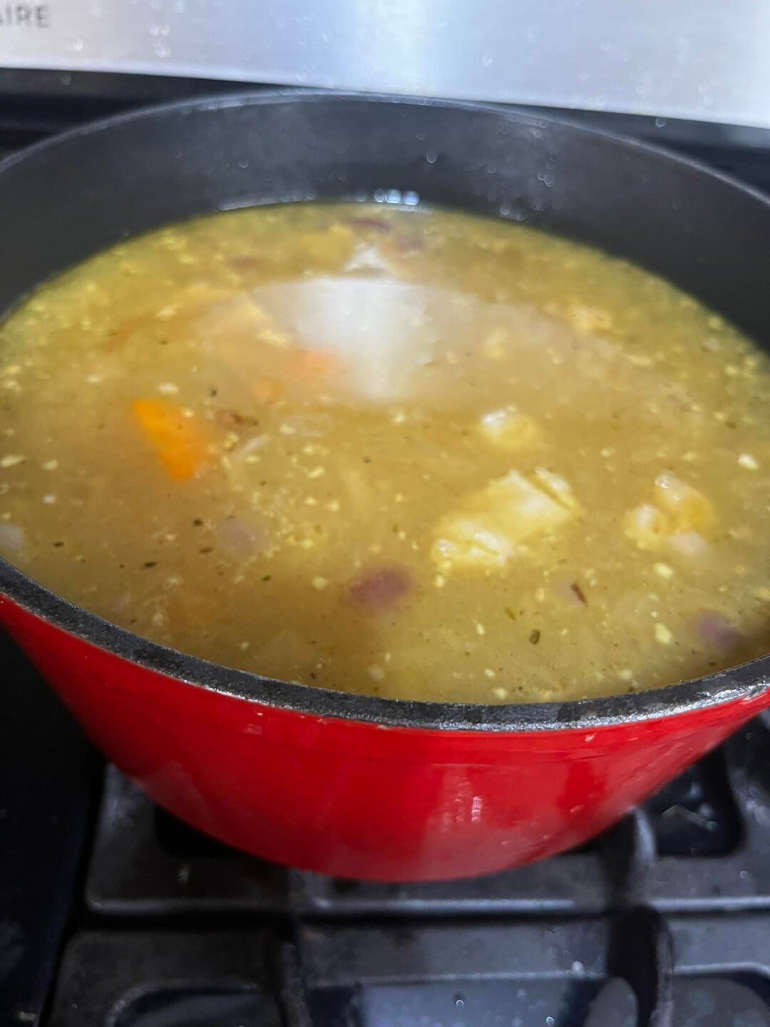 A nourishing bone Broth soup on the stove in a red bowl